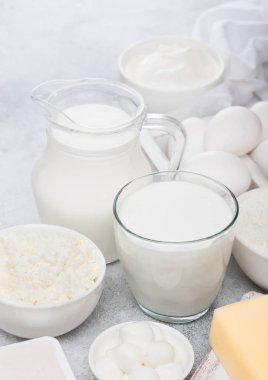 Beyaz masa arka plan üzerinde taze süt ürünleri. Kavanoz ve bir bardak süt, ekşi krema, peynir ve fırın un ve mozzarella kase. Yumurta ve peynir. 