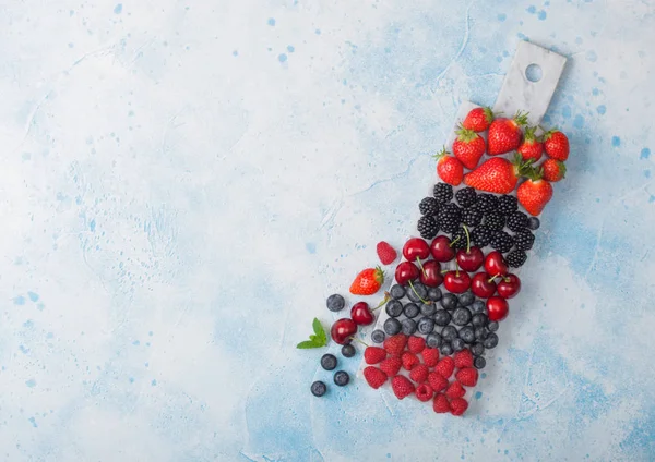 Φρέσκα βιολογικά φρούτα του καλοκαιριού αναμειγνύονται σε λευκό μάρμαρο στο φόντο του τραπεζιού με μπλε κουζίνα. Σμέουρα, φράουλες, βατόμουρα, βατόμουρα και κεράσια. Χώρος για κείμενο — Φωτογραφία Αρχείου