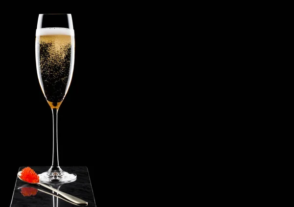 Elegant glas gul Champagne med röd kaviar på gyllene sked på marmor ombord på svart bakgrund. Utrymme för text — Stockfoto