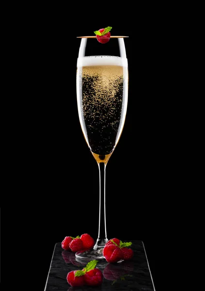 Elegant glas gul Champagne med rasspbery och färska bär med myntblad på pinne på svart marmor ombord på svart bakgrund. — Stockfoto