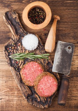 Kaliteli doğranmış hamburgerler, havan topu, tokmak ve ahşap arka planda et baltası. Üst görünüm