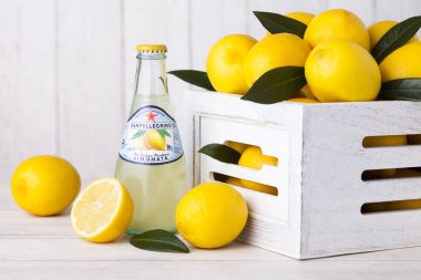 Londra, Uk - 27 Nisan 2018: Tahta arka planda cam şişe San Pellegrino soda ve bambu sepetinde taze limonlar. İtalya 'dan ithal edildi ve Nestle tarafından dağıtıldı..