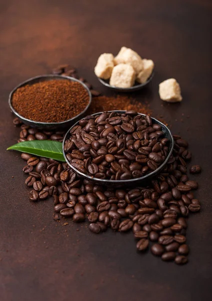 Verse rauwe biologische koffiebonen met gemalen poeder en rietsuiker blokjes met koffie TREA blad op bruine achtergrond. — Stockfoto