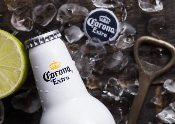 LONDON, UK - APRIL 27, 2018: Steel Bottle of Corona Extra Beer on wooden background with bottle opener and ice cubes.Top view