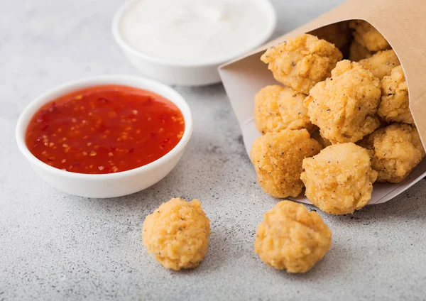 Kıtır kıtır güney tavuk patlamış mısırı hafif arka plandaki fast food yemekleri için kağıt kutuda ısırıyor. Tatlı biber ve ekşi krema sosu