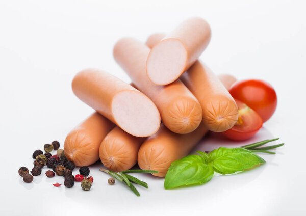 Классические колбасы из свинины с перцем и базиликом и помидорами черри на белом фоне
. 