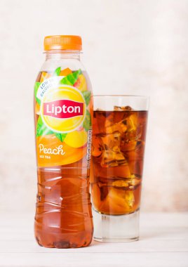LONDON, İngiltere - SEPTEMBER 03, 2018: Ahşap üzerine şeftali aromalı buzlu Lipton Ice Tea ile plastik şişe ve cam.