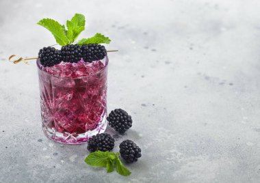 Arka planda böğürtlen, buz ve nane aromalı ferahlatıcı bir yaz kokteyli. Soda ve alkol karışımı. Metin için boşluk