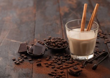 Tarçınlı kristal bardak İrlanda kremalı baileys likörü, kahve çekirdekleri ve koyu ahşap arka planda koyu çikolatalı toz. Metin için boşluk