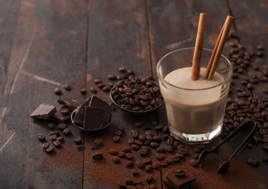 Tarçınlı kristal bardak İrlanda kremalı baileys likörü, kahve çekirdekleri ve koyu ahşap arka planda koyu çikolatalı toz. Metin için boşluk