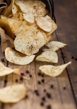 Patates cipsi çıtır çıtır cipsler ve çelik kovada karabiber, ahşap masa arkasında. Üst görünüm
