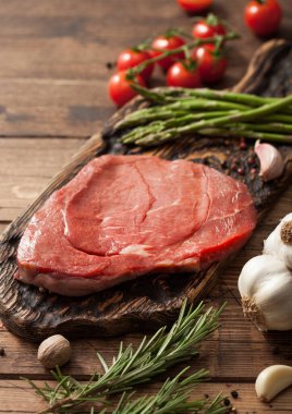 Biftek haşlama, tahtanın üzerinde taze çiğ dilim sarımsak, kuşkonmaz ve ahşap zemin üzerinde tuz ve biberli domatesler. Makro