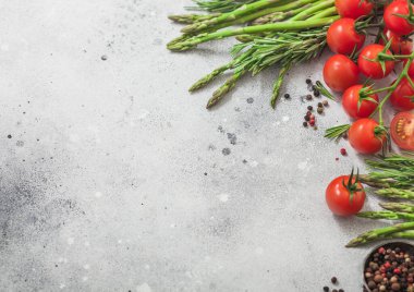 Hafif gıda arka planında sağlıklı vişneli domates, kuşkonmaz ve biberiye ve biber var. Metin için boşluk
