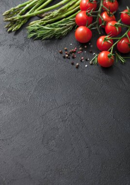 Kuşkonmaz, kiraz domates ve biberiye ile siyah yemek arka planda kara biber.