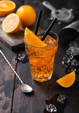 Portakal dilimli yüksek bardak aperol spreyli yaz kokteyli ve ahşap arka planda jigger ve kokteyl karıştırıcı. Buz küpleri ve siyah saman.