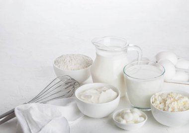 Beyaz arka planda taze süt ürünleri. Kavanoz ve bir bardak süt, bir kase ekşi krema, süzme peynir, un ve mozzarella. Yumurta ve peynir.. 