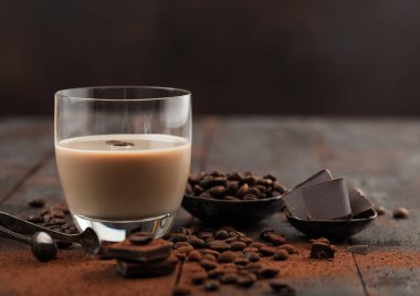 Bir bardak İrlanda kremalı baileys likörü kahve çekirdekleri ve koyu ahşap arka planda koyu çikolatalı pudra. Metin için boşluk