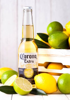 Londra, İngiltere - 27 Nisan 2018: Tahta arka planda taze limon ve limonlu bir şişe Corona Extra Birası. Corona, yapımcı Grupo Modelo.