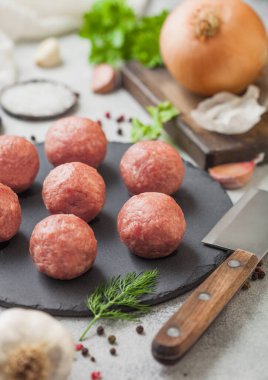 Taş tahtada taze çiğ köfteler, biber, tuz ve sarımsak arkaplanda dereotu, maydanoz ve dereotlu. Üst görünüm