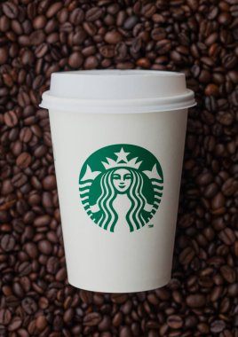 LONDON, İngiltere - 09 Eylül 2020: Starbucks kahvesini taze çiğ kahve çekirdeğinin üstüne koymak için kağıt bardak.