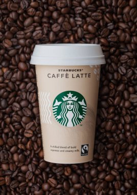 LONDON, İngiltere - 09 Eylül 2020: Taze çiğ kahve çekirdeğinin üstüne Starbucks Cafe Latte 'nin kağıt bardağı.
