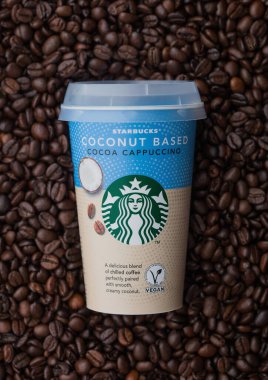 LONDON, İngiltere - TEPTEMBER 09, 2020: Taze çiğ kahve çekirdeğinin üzerinde Starbucks hindistancevizi tabanlı kapuçino kahvesi.