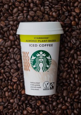 LONDON, İngiltere - 09 Eylül 2020: Starbucks Badem bitkisinin kağıt fincanı taze çiğ kahve çekirdeklerinin üzerine buzlu kahve tabanlı.