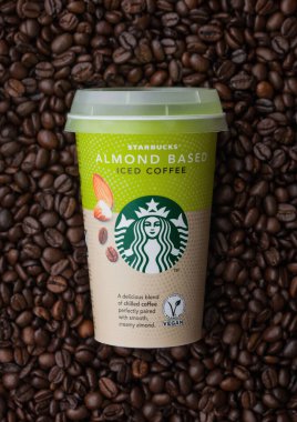 LONDON, İngiltere - 09 Eylül 2020: Starbucks Badem 'in kağıt bardağı taze çiğ kahve çekirdeklerinin üstüne buzlu kahve.