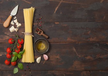 Çeri domatesli çiğ spagetti ve fesleğen, sarımsak ve yağ parmesan peyniri ve tuz ve ahşap zemin üzerinde biber. Metin için boşluk