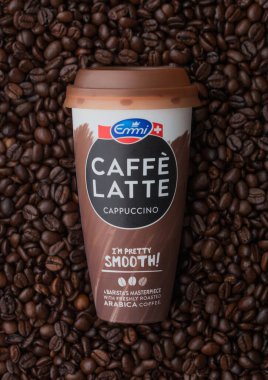 LONDON, İngiltere - SEPTEMBER 09, 2020: Estetik fincan Emmi Caffe Latte cappuccino taze çiğ kahve çekirdeklerinin üstünde soğuk kahve.