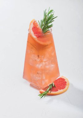 Yaz ferahlatıcı kırmızı greyfurt kokteyli modern lüks viski bardağında meyve dilimi ve beyaz arka planda biberiye. Sert ışık