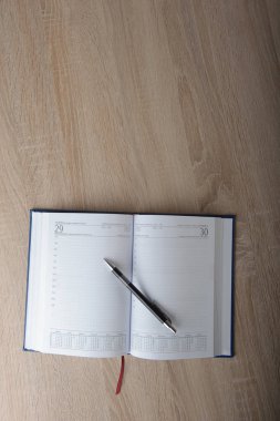 Ahşap masadaki kalemli defter.