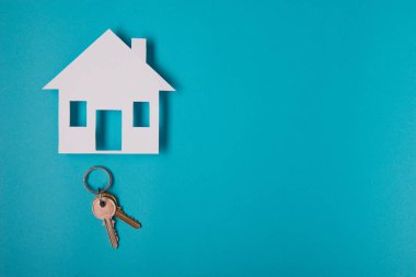 Gümüş anahtar ev şekil üzerinde mavi arka plan ile. Üstten Görünüm.