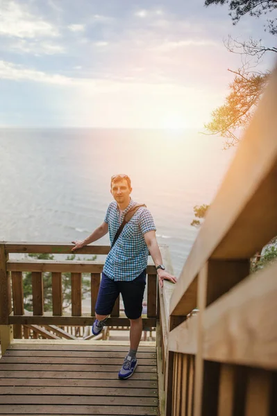 Mladý Muž Sedí Dřevěných Schodech Parku Usmívá — Stock fotografie