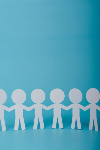абстрактные бумажные люди, держащиеся за руки на синем фоне