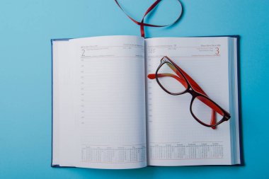 Fotokopi alanı ve ofis malzemeleriyle iş planlaması. Mavi arkaplanda kırmızı gözlük