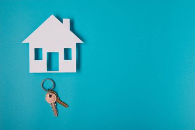 Gümüş anahtar ev şekil üzerinde mavi arka plan ile. Üstten Görünüm.