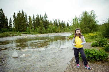 Kadın turist dağ nehir kenarında duran.