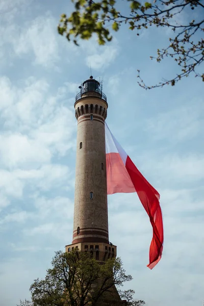 Old Brick Stone Lighthouse with polish national flag