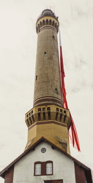 Old Brick Stone Lighthouse with polish national flag