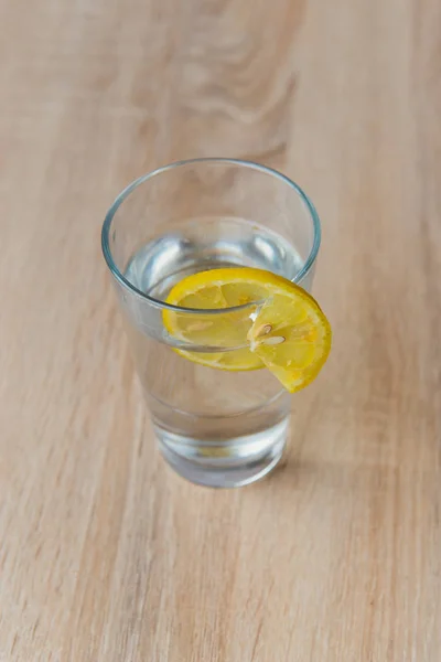 Szkło z wodą i cytryną na drewnianym stole — Zdjęcie stockowe
