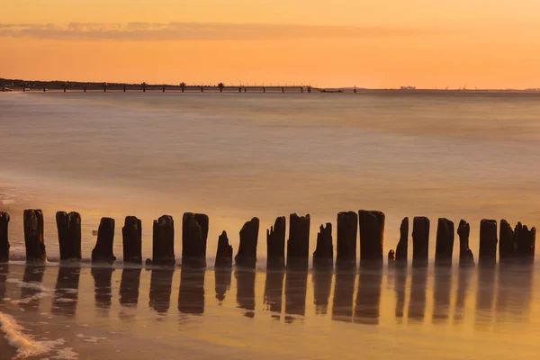 Rompeolas de madera al atardecer en el Mar Báltico — Foto de Stock