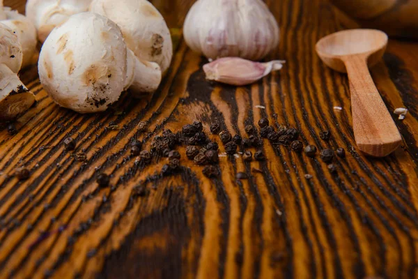 Świeże grzyby i czosnek na drewnianej płycie — Zdjęcie stockowe
