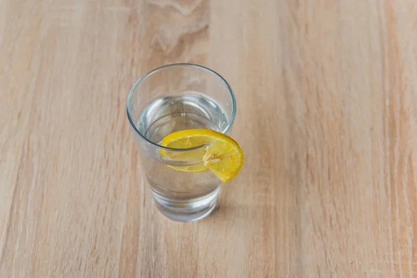 Vaso con agua y limón sobre mesa de madera — Foto de Stock