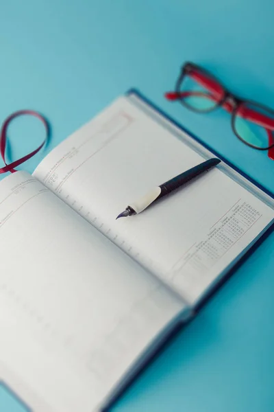 Caderno sobre papel azul. diário aberto e caneta para gravar — Fotografia de Stock