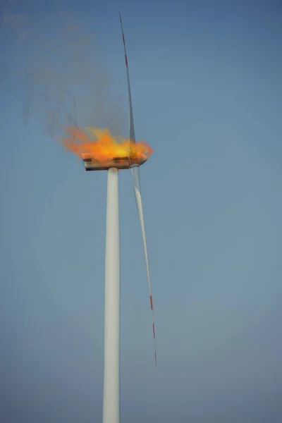 Turbina eolica Eco potenza nella giornata di sole sotto il fuoco. Fiamme di fuoco e fumo nero che fuoriescono . — Foto Stock