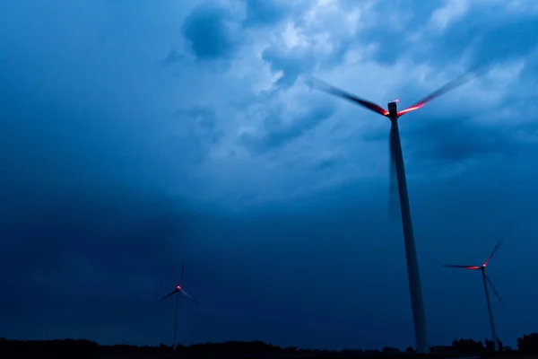 Turbine eoliche su una drammatica nuvole blu scuro nel cielo. La tempesta sta arrivando. spia rossa sul mulino a vento . — Foto Stock