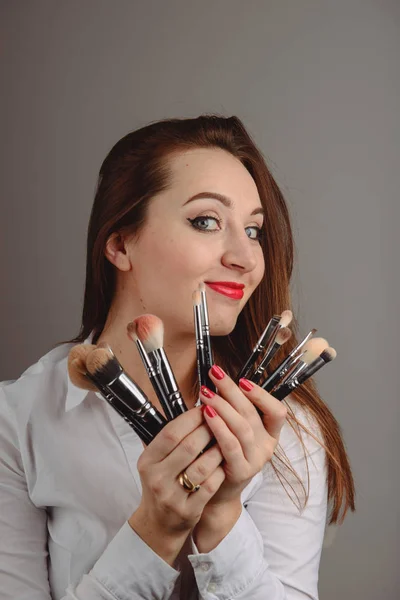 Kvinna som innehar en uppsättning kosmetiska borstar för smink, — Stockfoto