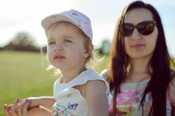 Madre e figlia felici nel parco. Scena di bellezza natura con stile di vita familiare all'aperto. Famiglia felice che riposa insieme sull'erba verde, divertendosi all'aperto. Felicità e armonia nella vita familiare — Foto Stock