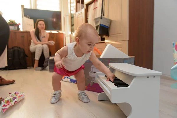 Hermosa niña jugando piano de juguete en la sala de luz —  Fotos de Stock